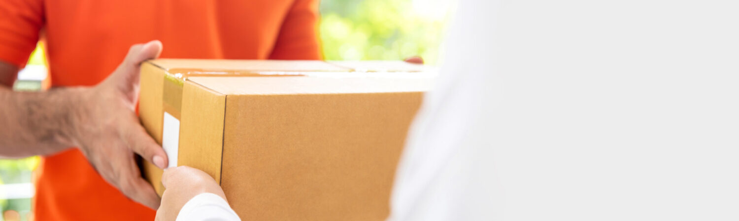 Courier service delivery man giving parcel box to customer Courier service delivery man in orange uniform giving parcel box to customer at home, panoramic banner with copy space